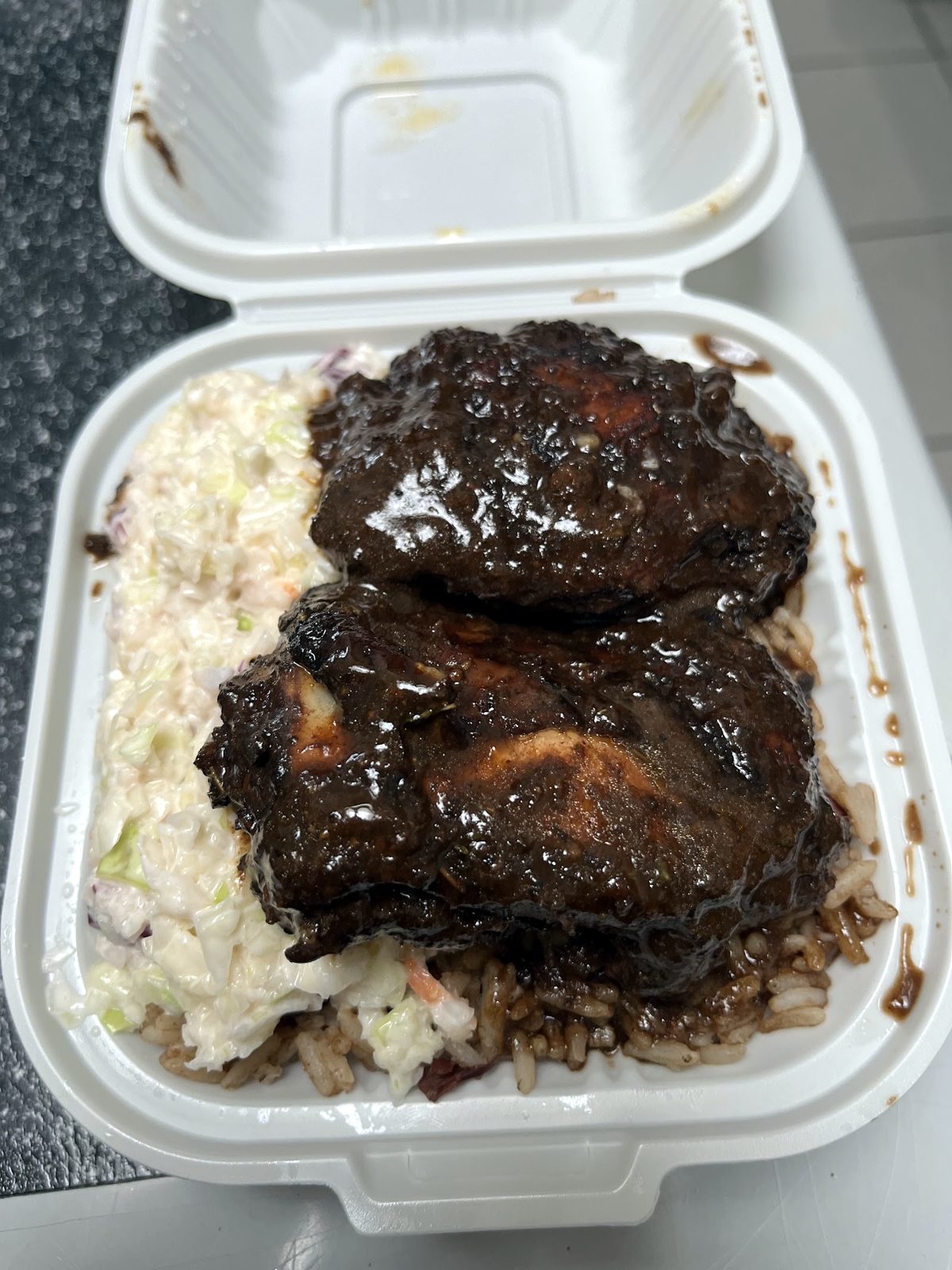 Jerk chicken meal with coleslaw and rice and peas